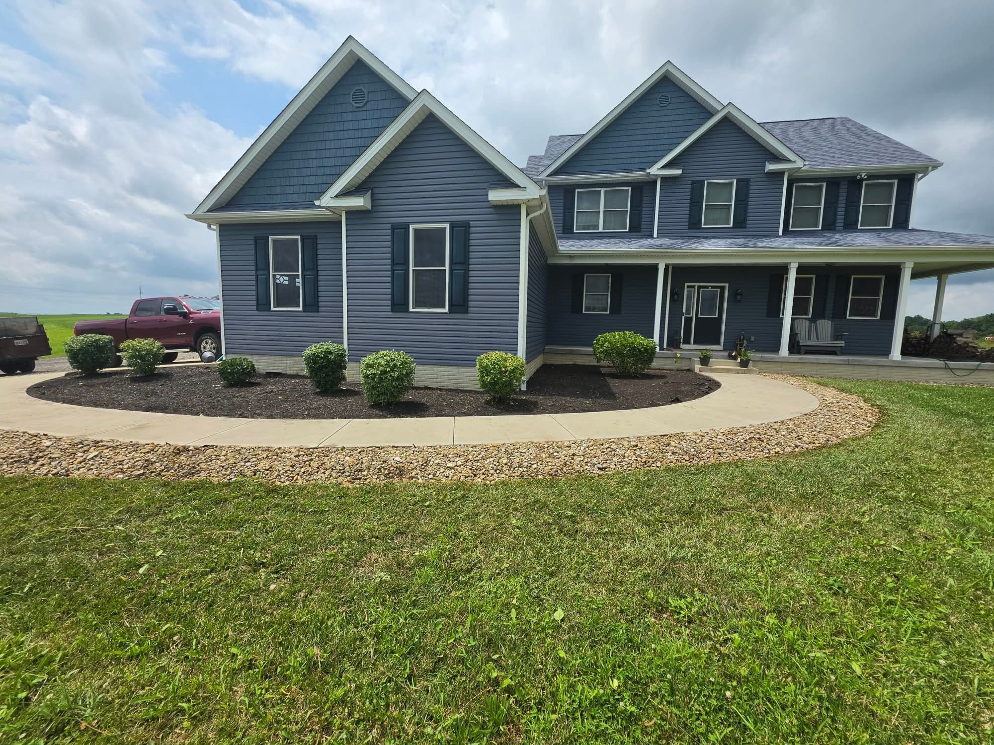 Restored foundation beds with fresh dark mulch, shaped shrubs, river rock border and mowed lawn